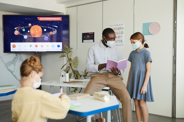 A modern classroom scene with students using interactive whiteboards and tablets to engage in a science lesson focused on renewable energy. The teacher is facilitating group discussion, promoting collaborative learning.