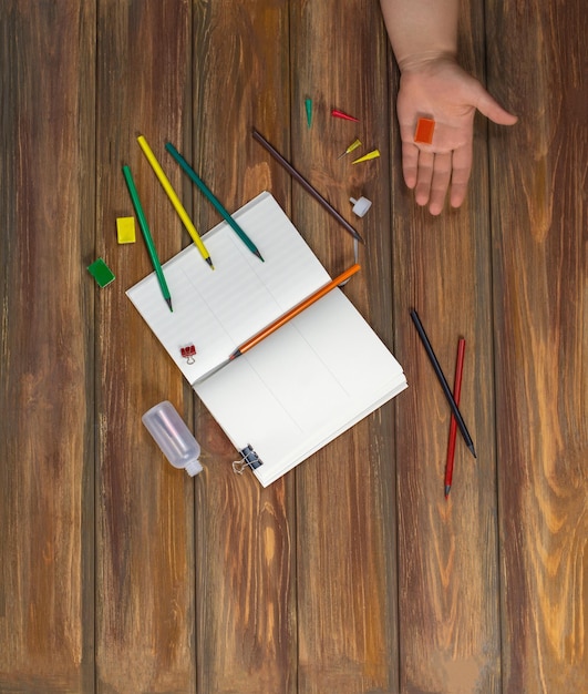 A close-up shot of an SAT test booklet with pencils and an eraser on top, partially obscured by a student's hand. The desk is cluttered with study guides.