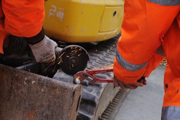 A close-up of construction workers repairing a section of a bridge, with heavy machinery and safety equipment visible. The focus should be on the hands-on work being done to improve infrastructure.