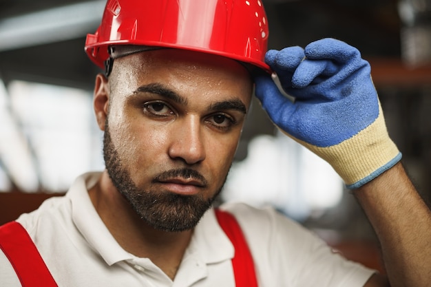 A close-up shot showing a construction worker wearing a hard hat and safety vest, inspecting a newly paved section of road. The machinery is in the background, and the focus is on the worker's focused expression, symbolizing the labor force involved in the infrastructure projects.